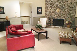 Two comfy chairs & a red couch surround the fireplace area