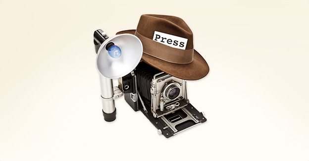 Antique camera and flash with an old hat on top, with a press badge in its band